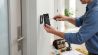 Handyman installing a wireless smart video doorbell on a house wall for home security and surveillance