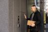 Man ringing intercom with camera near building entrance